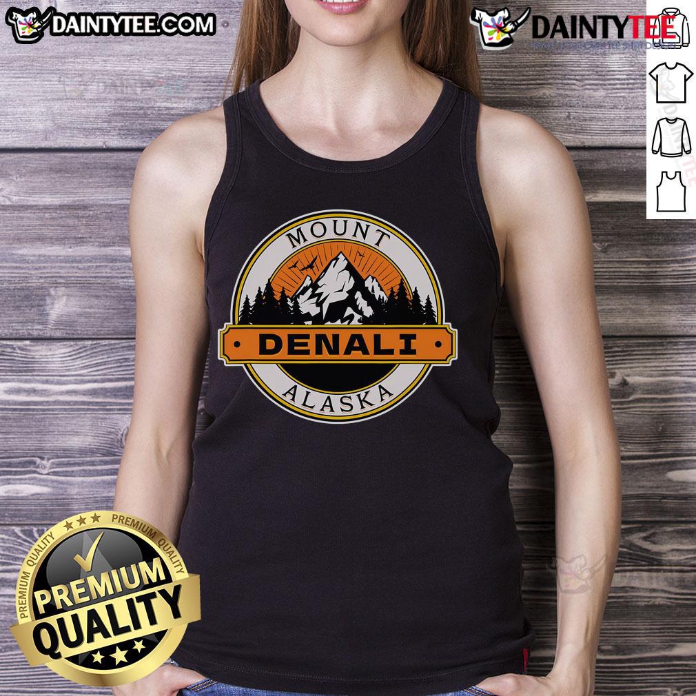 Model wearing a Good Mount Denali Alaska tank top against a scenic mountain backdrop, showcasing outdoor adventure style.