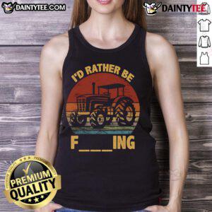 Farmer wearing a tank top with 'Good I'd Rather Be Farming' joke, standing next to a tractor on a sunny day.