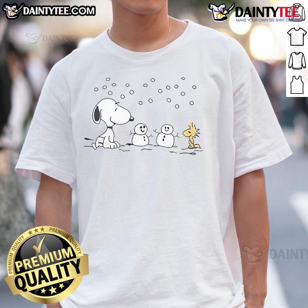 Alt Text: Cute Peanuts Snoopy and Woodstock building a snowman on a winter-themed t-shirt, perfect for holiday wear.
