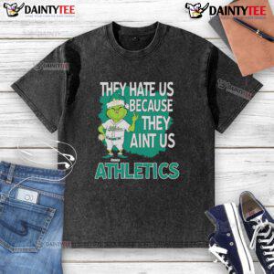 Alt Text: Awesome Athletics Grinch Christmas T-Shirt featuring 'They Hate Us Ain't Us' design for festive sports fans.