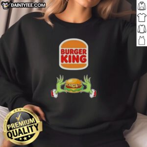 Good Grinch hands holding a festive Burger King sweatshirt, perfect for a Merry Christmas celebration.