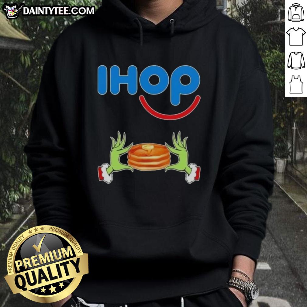 Good Grinch hands holding a mug, wearing a Merry Christmas IHOP hoodie in festive colors.