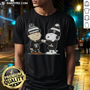 Charlie Brown and Snoopy fist bump on a football T-shirt, celebrating Peanuts with Las Vegas Raiders theme.