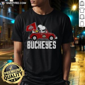 Alt Text: Premium Snoopy and Woodstock driving a car wearing Ohio State Buckeyes flag t-shirt, perfect for fans.